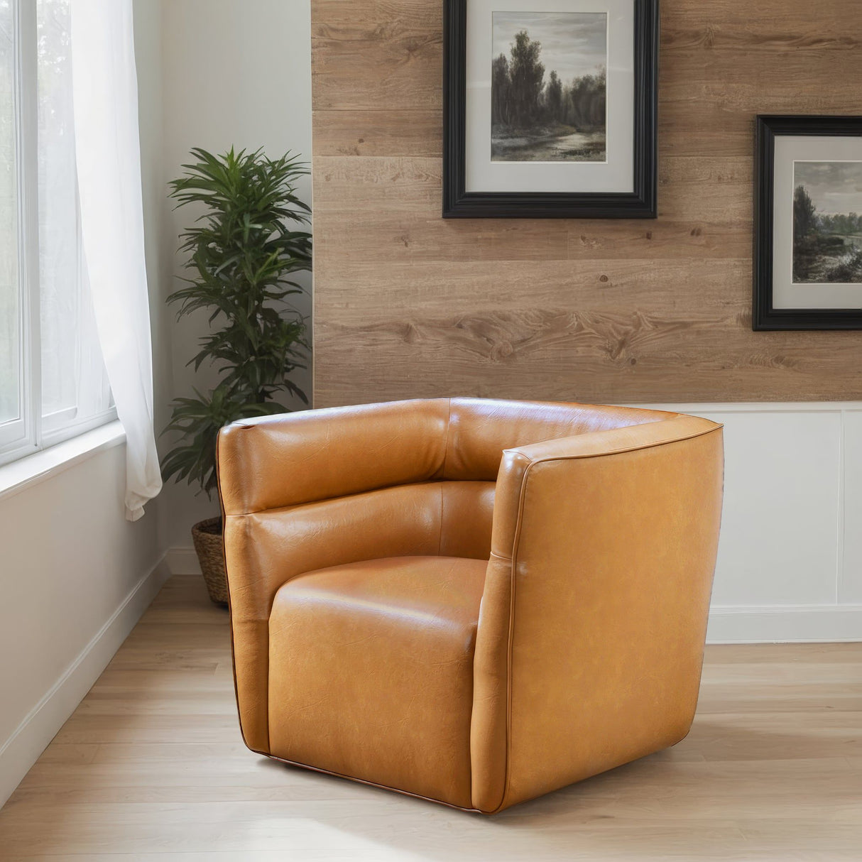 The Callan Swivel Chair in tan graces a room featuring light wood floors and a wood-paneled wall. Large framed art and a tall plant enhance the backdrop, while natural light streams through a window adorned with sheer curtains.