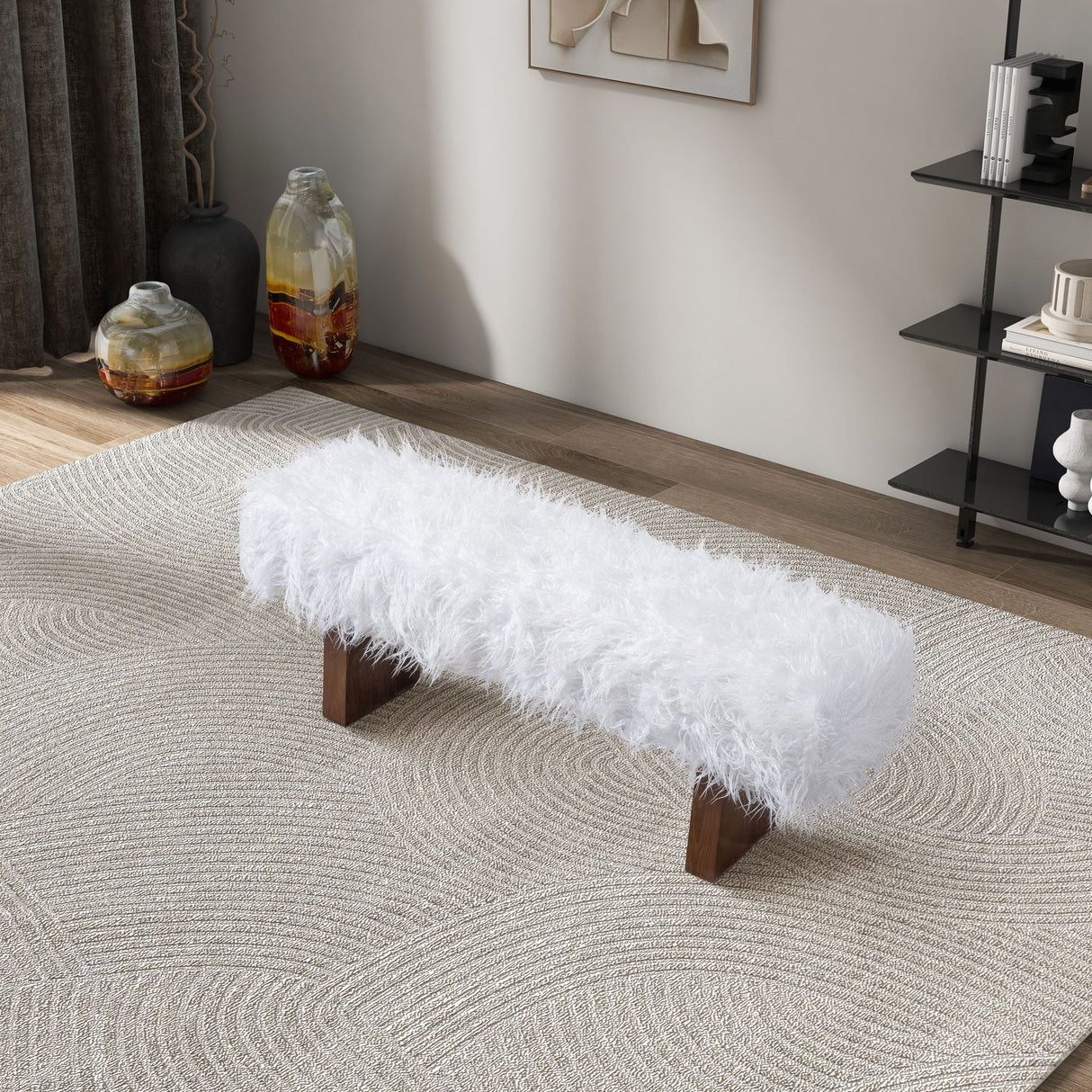 The Henley - Fur Bench in White Khaki, with its fluffy design and wooden legs, is positioned on a textured rug. Nearby are a shelf and two decorative vases, creating a modern living room setup.