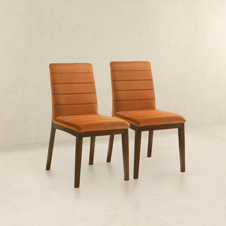 A pair of Ines Modern Dining Chairs in brown with wooden legs and horizontal stitching on the backrests are side by side on a light floor against a neutral wall.