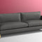The Bowen 91" Sofa, featuring a modern design with two seat cushions and sleek armrests, stands on short metallic legs. It is set against a two-tone background with pink and white walls.