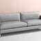 The Bowen 91" Sofa, with its modern design, features a sleek grey finish and clean lines. It includes two large cushions and is complemented by slim, angular armrests and elegant gold-colored legs. Placed against a soft pink wall and light grey floor, it adds a sophisticated touch to the room.