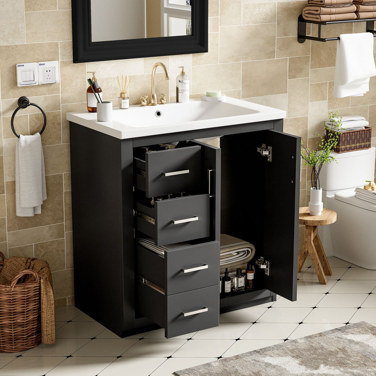 The freestanding vanity set with a black cabinet includes a ceramic sink combo, three open drawers, and soft-closing doors revealing towels and bottles. It features a white countertop. The nearby area has tiled flooring, along with a wicker basket, stool, and stack of towels.