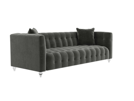 The Bea Velvet Tufted Sofa in dark green comes with two matching cushions and is supported by clear legs. This sofa boasts a modern design with a high back and armrests, offering a plush and elegant appearance.