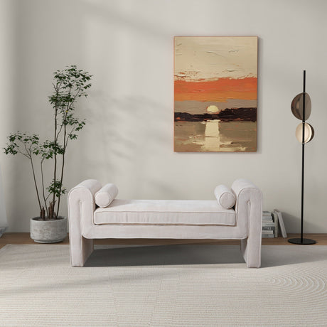 A minimalist living room with the Regent Bench in cream, cylindrical cushions, a tall potted plant on the left, a modern floor lamp on the right, and a sunset over water painting on the back wall.