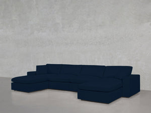A 6-Seat Modular Double Chaise Sectional in modern dark blue with plush cushions sits against a plain light gray textured wall on a polished floor.