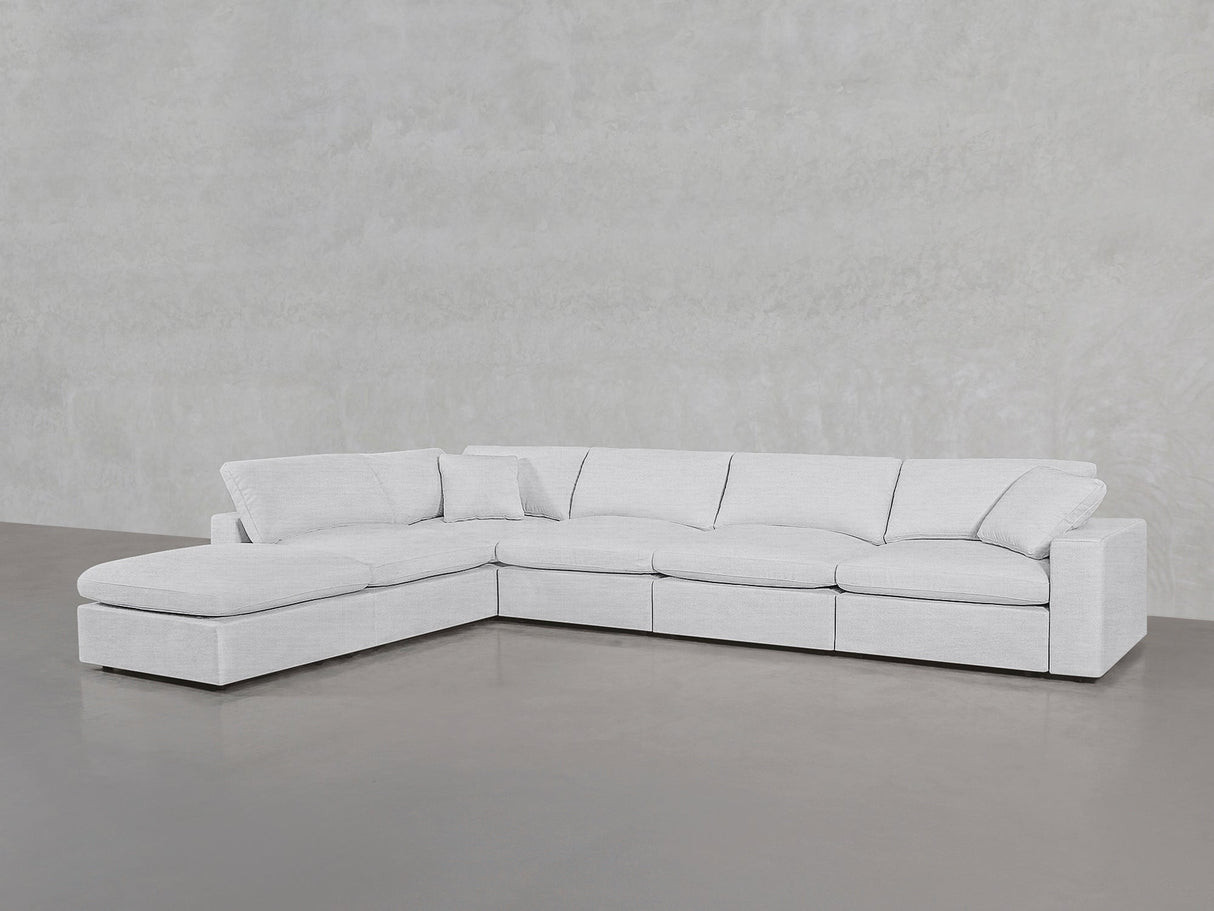 The 6-Seat Modular Corner Lounger Sectional, featuring a modern design in light gray with plush cushions and clean lines, sits on a smooth gray floor against a lightly textured wall.