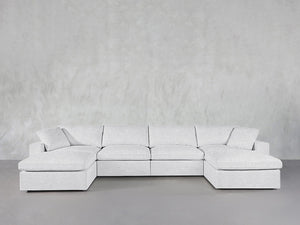 A 6-Seat Modular Double Chaise Sectional in light gray is displayed against a minimalist, light gray textured wall and floor.