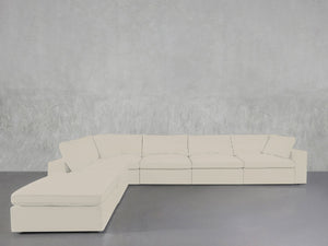 A 6-Seat Modular Corner Lounger Sectional in light beige, featuring an L-shaped design, is set against a textured grey wall and rests on a smooth grey floor.