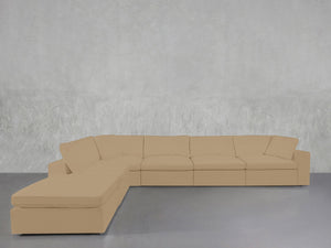 A 6-Seat Modular Corner Lounger Sectional in beige, featuring multiple cushions, is arranged against a plain light-gray textured wall on a smooth gray floor.