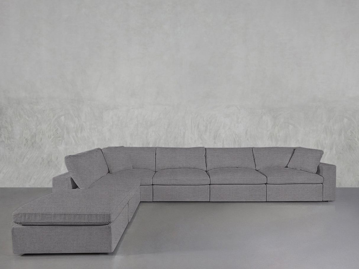 The 6-Seat Modular Corner Lounger Sectional in light gray, featuring plush cushions, is arranged on a smooth gray floor against a textured light gray wall.
