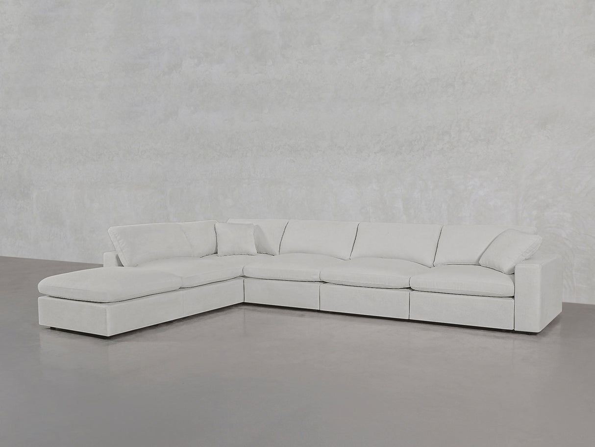 A spacious, modern 6-Seat Modular Corner Lounger Sectional in light gray with plush cushions and a left-side chaise is set against smooth, light-colored walls and flooring.
