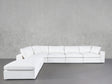 The 6-Seat Modular Corner Lounger Sectional in white, with plush cushions, is arranged in an L-shape against a plain light gray textured wall and smooth gray floor.