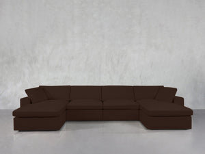 A 6-Seat Modular Double Chaise Sectional in dark brown sits against a plain light gray wall atop a shiny, light-colored floor.