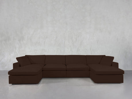 A 6-Seat Modular Double Chaise Sectional in dark brown sits against a plain light gray wall atop a shiny, light-colored floor.