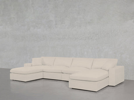 The 6-Seat Modular Double Chaise Sectional, featuring clean lines and plush cushions in light beige, is set against a gray textured wall and floor, with a chaise lounge on each end for modern comfort.
