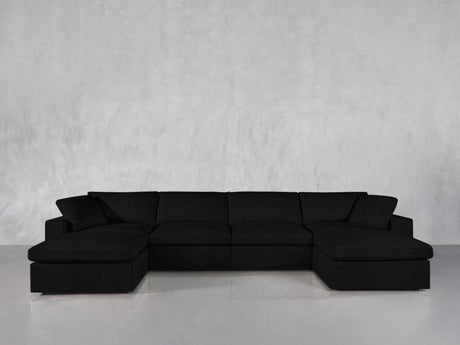 The 6-Seat Modular Double Chaise Sectional with wide armrests and plush cushions is arranged against a light gray textured wall and a smooth, light-colored floor.