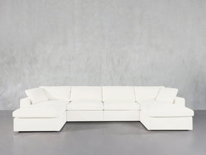 The 6-Seat Modular Double Chaise Sectional features wide armrests and plush cushions, showcased in modern white against a light gray wall and gray floor.