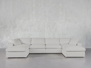 The 6-Seat Modular Double Chaise Sectional with clean lines and plush cushions is arranged in front of a light gray textured wall on a glossy floor.
