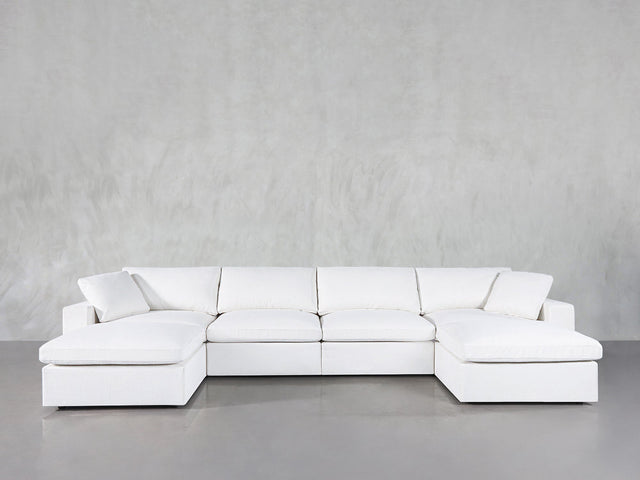 The 6-Seat Modular Double Chaise Sectional, featuring a modern design with clean lines and plush cushions, is placed on a smooth gray floor against a light gray textured wall.