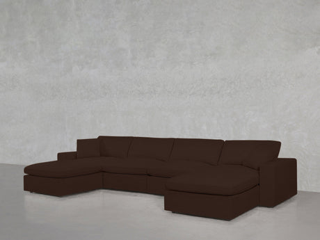 A 6-Seat Modular Double Chaise Sectional in dark brown, featuring low, wide cushions and armrests, is placed against a plain light gray textured wall on a glossy floor.