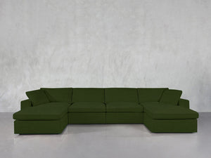 A 6-Seat Modular Double Chaise Sectional in dark green stands against a light gray textured wall and glossy gray floor.