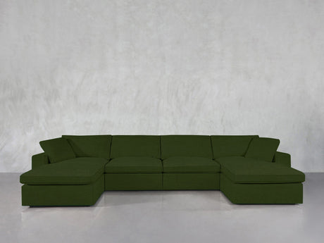A 6-Seat Modular Double Chaise Sectional in dark green stands against a light gray textured wall and glossy gray floor.
