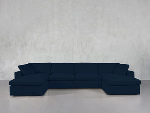A 6-Seat Modular Double Chaise Sectional in dark blue is arranged against a plain light gray wall and a glossy gray floor.