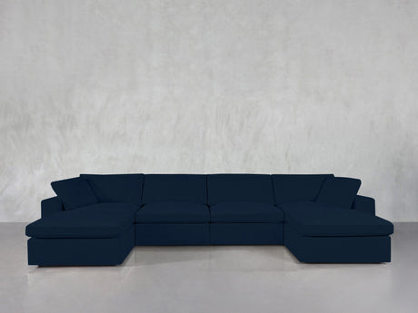 A 6-Seat Modular Double Chaise Sectional in dark blue is arranged against a plain light gray wall and a glossy gray floor.