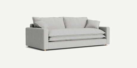 The Meriwether Sofa, featuring a minimalist design, is showcased against a plain background. It boasts plush cushions, wide armrests, and wooden legs in a modern light gray hue.