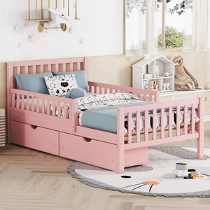 A cozy children's bedroom includes a Platform Bed With Guardrails on both sides and 2 storage drawers in pink. The playful bedding features cartoon prints, complemented by a soft rug, a small toy-filled bookshelf, and natural light streaming through the window.