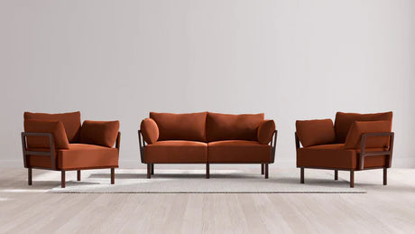 The Indoor Jack 2-Seater Sofa + Armchair Set in Balsa includes a contemporary ensemble featuring two armchairs and a sofa, all upholstered in burnt orange fabric. Arranged on a light-colored rug against a neutral wall, this setup delivers a chic and minimalist atmosphere.