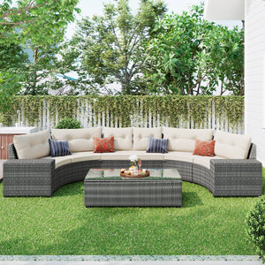 The 8 Pieces Outdoor Wicker Round Sofa Set features a curved half-moon sectional sofa with beige cushions on a green lawn, along with a rectangular glass-topped coffee table and tray. A white fence and lush greenery complete the background, displaying an elegant and weather-resistant outdoor setup.