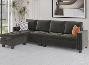 A modern living room featuring the Belffin Reversible Sectional Convertible Storage in dark green, paired with a matching ottoman on a light gray rug. The sectional is adorned with a black and white patterned pillow and an orange throw pillow for added color. A large plant completes the corner, while abstract art adorns the wall.
