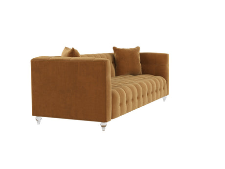 The Bea Velvet Tufted Sofa is a luxurious piece featuring plush, mustard-yellow velvet upholstery with a tufted design and square arms. It includes clear legs and comes with two matching throw pillows, offering a cozy and stylish appearance.