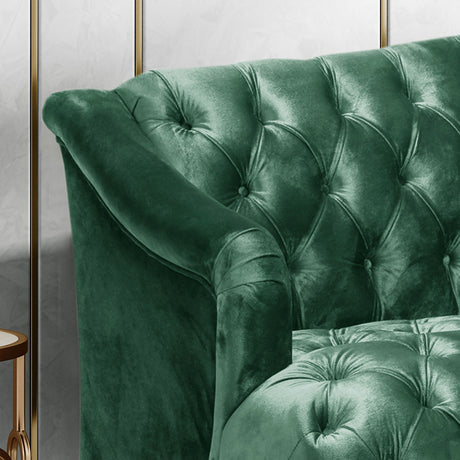 A close-up of an elegant, deep green velvet "Comfy 3 Seat Sofa With Wooden Legs" featuring a tufted back and plush cushions, positioned against a wall with a hint of gold trim visible.