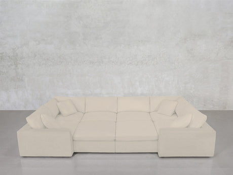 An 8-Seat Modular Closed Pit in beige, paired with four matching cushions, is arranged in a U-shape against a light gray textured wall and concrete floor.