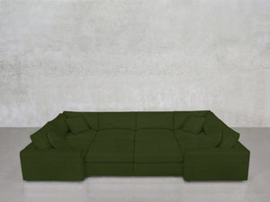 The 8-Seat Modular Closed Pit, in deep green with wide seats and matching pillows, sits before a smooth, light gray textured wall on a pale floor.