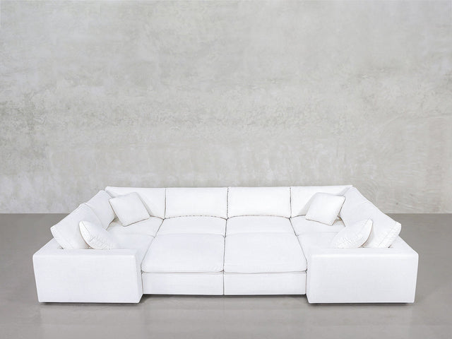 An 8-Seat Modular Closed Pit sectional in modern white, with four matching cushions, set against a light gray wall and polished concrete floor.