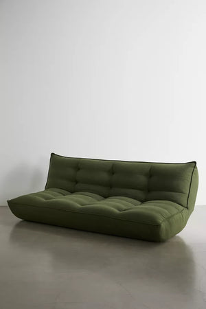 Greta XL Sleeper Sofa in green, featuring a modern low-profile design with tufted cushions, showcased on a polished concrete floor against a plain white wall.