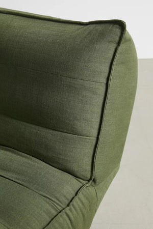 Close-up of the Greta XL Sleeper Sofa, a modern green fabric piece featuring a cushioned backrest and detailed stitching, set against a light gray background.
