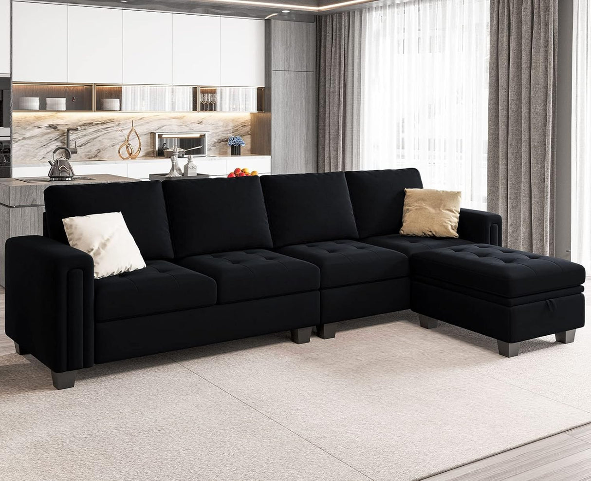 A modern living room features the Belffin Reversible Sectional Convertible Storage sofa in black, complete with an ottoman and beige cushions. The background showcases a sleek kitchen with white cabinets and a large window adorned with sheer curtains.