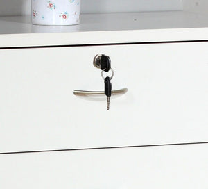 A 5 Drawer Chest in white with metal handles features a locking top drawer with a key inserted. A white container with a floral design is partially visible on the shelf above.
