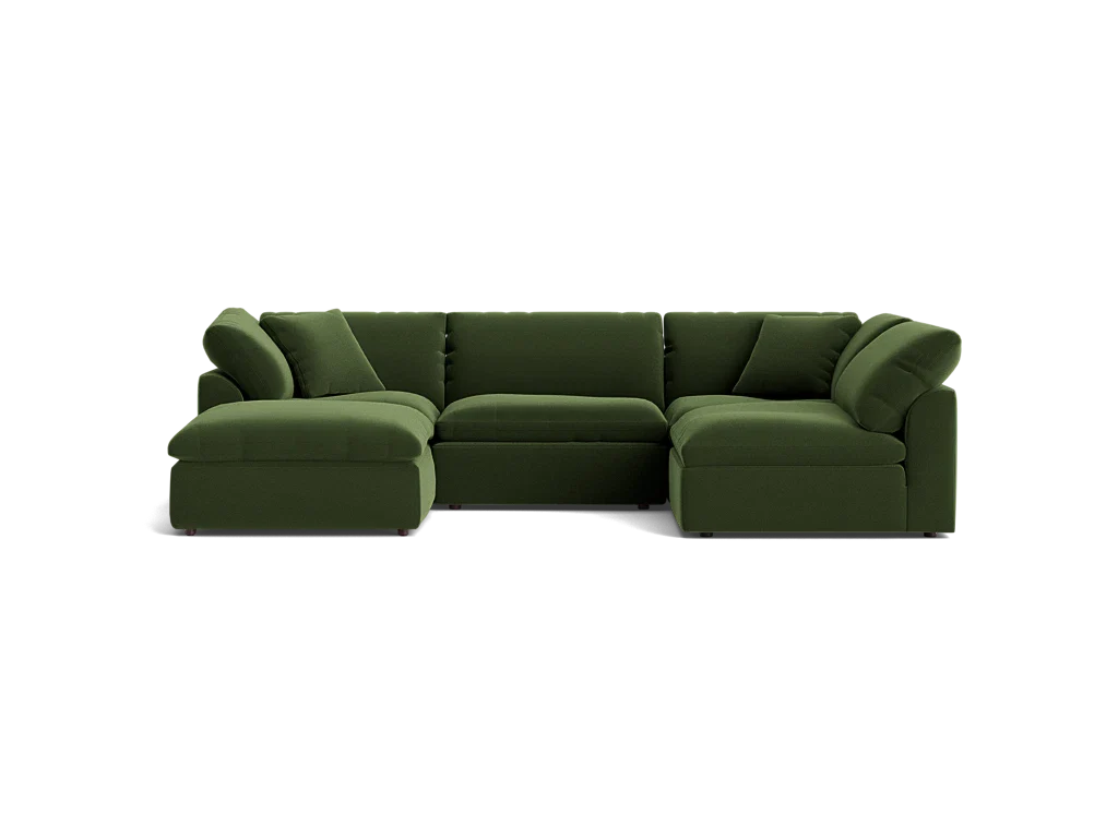 The Bryant U-Sofa Bumper Sectional is a spacious, dark green sectional sofa featuring a left-side chaise. Its plush and minimalist design is complemented by multiple cushions, all set against a simple black background.