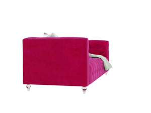 The Bea Velvet Tufted Sofa in a vibrant pink features modern tufted upholstery and transparent legs, draped with a light gray blanket on one side, all set against a white background.