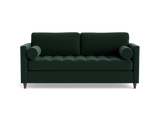 The Briar Sleeper Sofa is a dark green, mid-century modern piece featuring two cylindrical arm cushions and tufted seating. It is elevated on short wooden legs and presented against a plain black background.