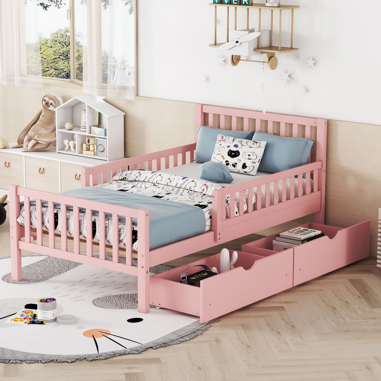A children's bedroom includes a Platform Bed With Guardrails On Both Sides And 2 Storage Drawers, adorned with blue, cartoon-patterned bedding. A plush sloth toy sits on a cabinet, while wall-mounted shelves hold books and toys.