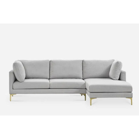 A modern light gray sectional sofa with three cushions and a chaise lounge on the right side. It features slim golden legs and two cylindrical accent pillows, set against a plain white background.