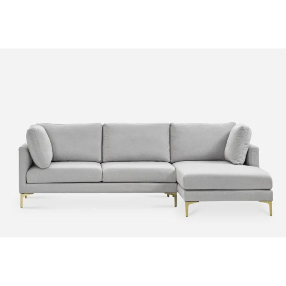 A modern light gray sectional sofa with three cushions and a chaise lounge on the right side. It features slim golden legs and two cylindrical accent pillows, set against a plain white background.