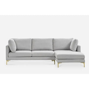 A modern light gray sectional sofa with three cushions and a chaise lounge on the right side. It features slim golden legs and two cylindrical accent pillows, set against a plain white background.