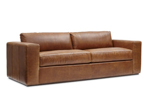 The Bolo Leather Sleeper in Carriage is a large, modern brown leather sofa featuring wide armrests and two seat cushions, set against a white background. Its design is sleek and contemporary.